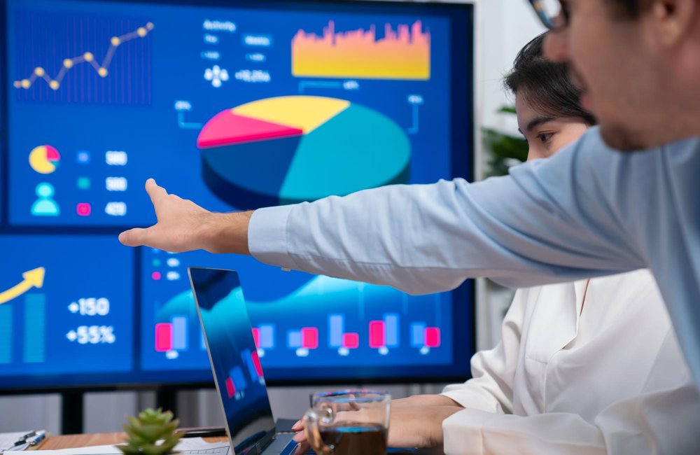 Dos analistas revisando un tablero de indicadores en pantalla